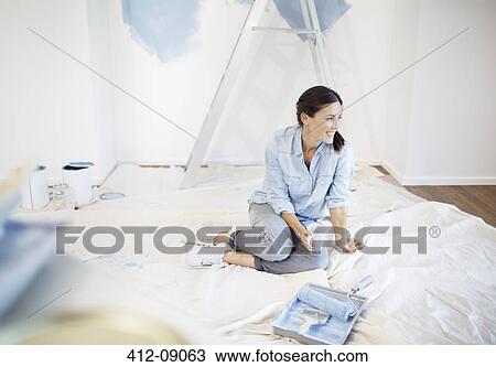 Stock Image - Woman drinking coffee surrounded by painting supplies. Fotosearch