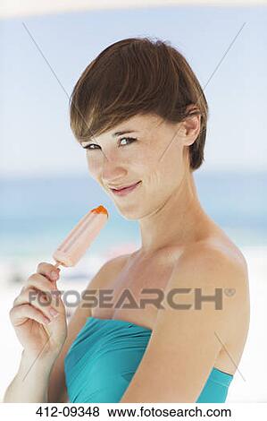 Woman eating flavored ice on beach View Large Photo Image Stock Photo - Woman eating flavored ice on beach. Fotosearch