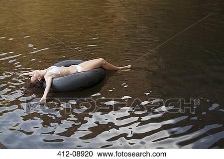 Stock Image - Woman floating in inner tube in river. Fotosearch