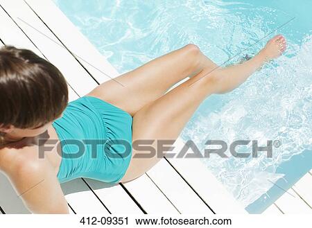 Stock Image - Woman in bathing suit relaxing poolside. Fotosearch