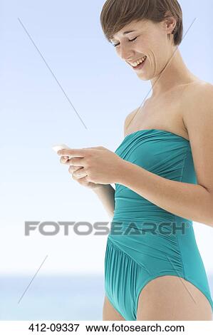 Stock Photo - Woman in bathing suit using cell phone. Fotosearch