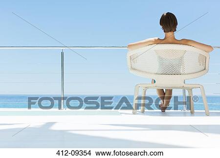 Woman in chair looking at ocean view View Large Photo Image Picture - Woman in chair looking at ocean view. Fotosearch