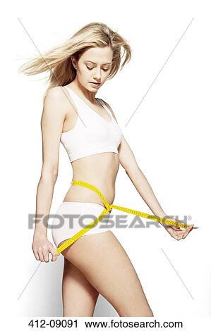 Stock Image - Woman measuring her waist. Fotosearch