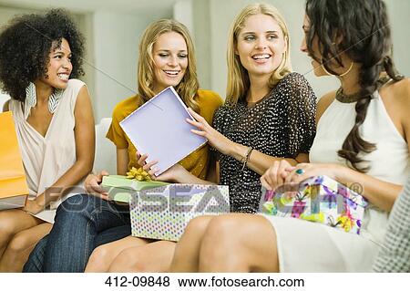 Stock Photo - Woman opening gifts at birthday party. Fotosearch