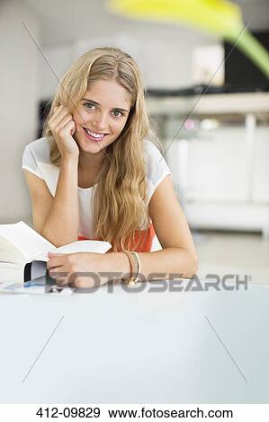 Woman reading book at table View Large Photo Image Stock Photo - Woman reading book at table. Fotosearch