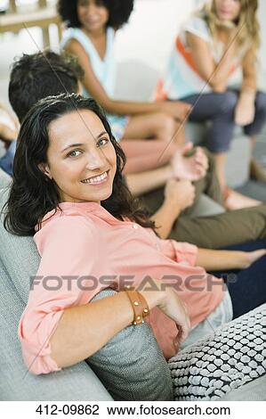Woman smiling on sofa at party View Large Photo Image Stock Image - Woman smiling on sofa at party. Fotosearch