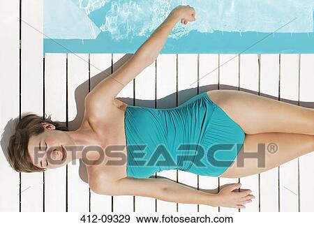 Woman sunbathing at poolside View Large Photo Image Stock Photo - Woman sunbathing at poolside. Fotosearch