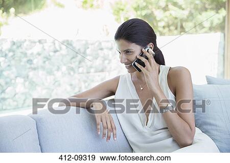 Woman talking on cell phone on sofa View Large Photo Image Stock Photo - Woman talking on cell phone on sofa. Fotosearch