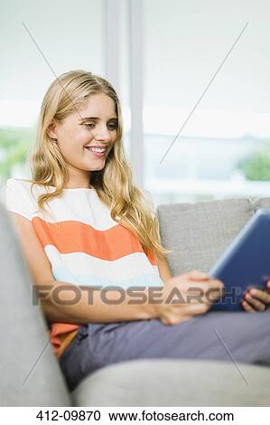 Woman using digital tablet on sofa View Large Photo Image Stock Image - Woman using digital tablet on sofa. Fotosearch