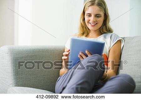 Woman using digital tablet on sofa View Large Photo Image Stock Image - Woman using digital tablet on sofa. Fotosearch