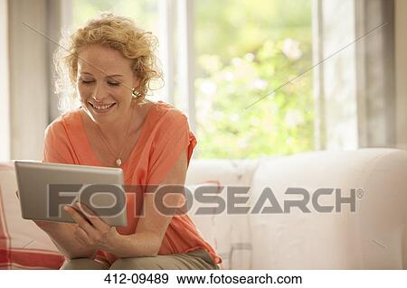 Woman using digital tablet on sofa View Large Photo Image Stock Photo - Woman using digital tablet on sofa. Fotosearch