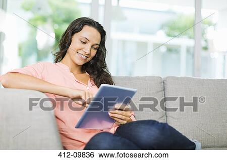 Woman using digital tablet on sofa View Large Photo Image Stock Photograph - Woman using digital tablet on sofa. Fotosearch