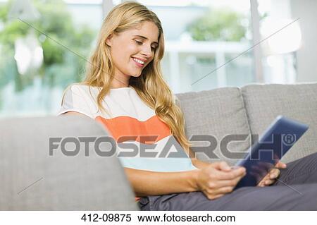 Woman using digital tablet on sofa View Large Photo Image Stock Photography - Woman using digital tablet on sofa. Fotosearch