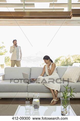 Stock Image - Woman using laptop on sofa. Fotosearch