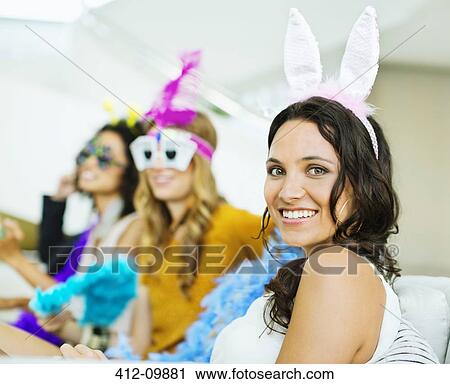 Stock Image - Woman wearing bunny ears at party. Fotosearch