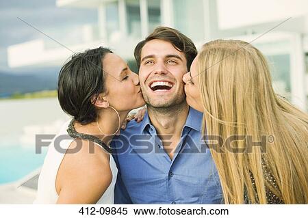 Women kissing man's cheek outdoors View Large Photo Image Stock Photography - Women kissing man's cheek outdoors. Fotosearch