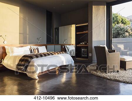 Stock Photograph - Armchair and bed in modern bedroom. Fotosearch
