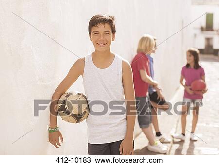 Boy holding soccer ball in alley View Large Photo Image Stock Image - Boy holding soccer ball in alley. Fotosearch