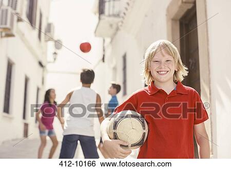 Boy holding soccer ball in alley View Large Photo Image Stock Photograph - Boy holding soccer ball in alley. Fotosearch