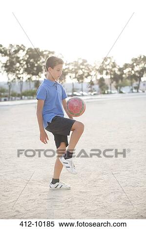 Boy kneeing soccer ball in sand View Large Photo Image Stock Photography - Boy kneeing soccer ball in sand. Fotosearch