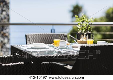 Stock Photo - Breakfast on luxury patio dining table overlooking ocean. Fotosearch