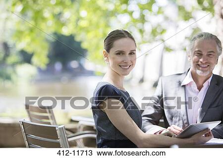Stock Image - Business people smiling at sidewalk cafe. Fotosearch