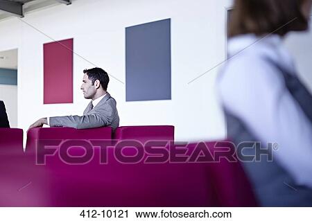 Stock Image - Businessman sitting in lobby. Fotosearch