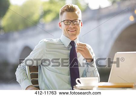 Stock Image - Businessman smiling at sidewalk cafe. Fotosearch