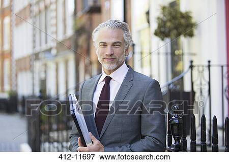 Businessman smiling on city street View Large Photo Image Stock Photo - Businessman smiling on city street. Fotosearch