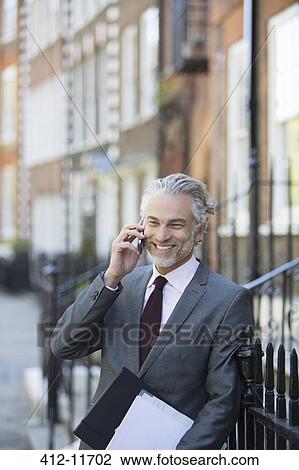 Businessman talking on cell phone on urban sidewalk View Large Photo Image Stock Image - Businessman talking on cell phone on urban sidewalk. Fotosearch