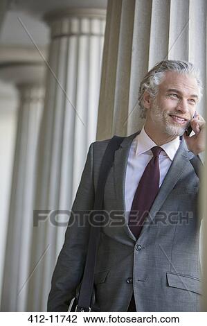 Stock Image - Businessman talking on cell phone outdoors. Fotosearch