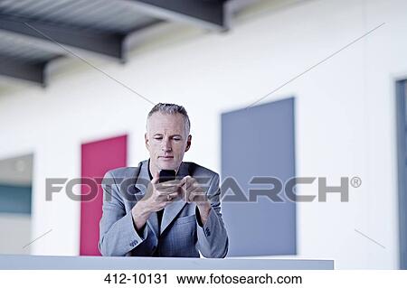 Businessman using cell phone in lobby View Large Photo Image Stock Image - Businessman using cell phone in lobby. Fotosearch