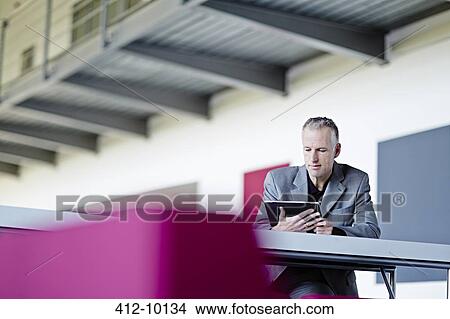 Picture - Businessman using digital tablet in lobby. Fotosearch