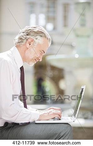 Businessman using laptop outdoors View Large Photo Image Stock Photo - Businessman using laptop outdoors. Fotosearch