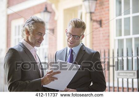 Businessmen looking at paperwork outdoors View Large Photo Image Stock Photo - Businessmen looking at paperwork outdoors. Fotosearch