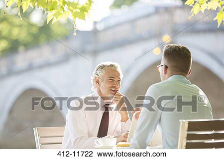 Businessmen talking at sidewalk cafe View Large Photo Image Stock Image - Businessmen talking at sidewalk cafe. Fotosearch