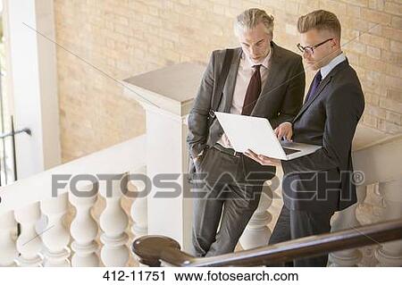Stock Image - Businessmen using laptop on steps. Fotosearch