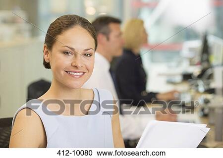 Stock Image - Businesswoman smiling in office. Fotosearch