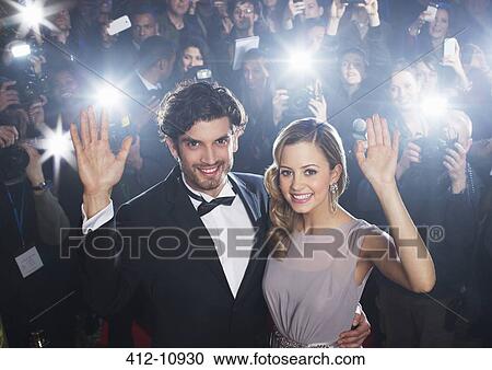 Celebrity couple waving on red carpet with paparazzi in background View Large Photo Image Stock Image - Celebrity couple waving on red carpet with paparazzi in background. Fotosearch