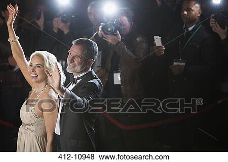 Stock Photo - Celebrity couple waving to paparazzi at red carpet event. Fotosearch