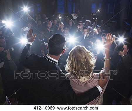 Stock Photo - Celebrity couple waving to paparazzi at red carpet event. Fotosearch