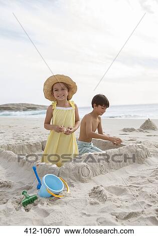 Stock Image - Children building sandcastle on beach. Fotosearch