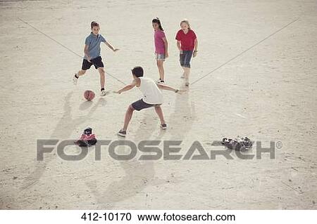 Stock Image - Children playing with soccer ball in sand. Fotosearch