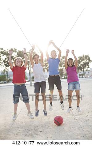 Stock Photo - Children playing with soccer ball in sand. Fotosearch