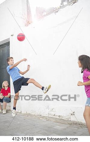 Stock Photo - Children playing with soccer ball in alley. Fotosearch