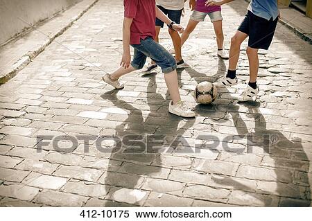 Children playing with soccer ball on cobblestone street View Large Photo Image Stock Photography - Children playing with soccer ball on cobblestone street. Fotosearch
