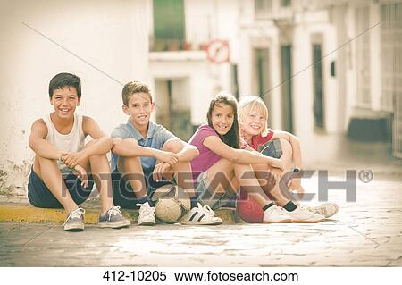 Stock Photography - Children with soccer balls sitting on city street. Fotosearch