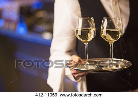 Close up bartender carrying white wine glasses on tray View Large Photo Image Stock Photo - Close up bartender carrying white wine glasses on tray. Fotosearch