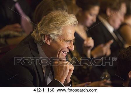 Stock Image - Close up of man laughing in theater audience. Fotosearch
