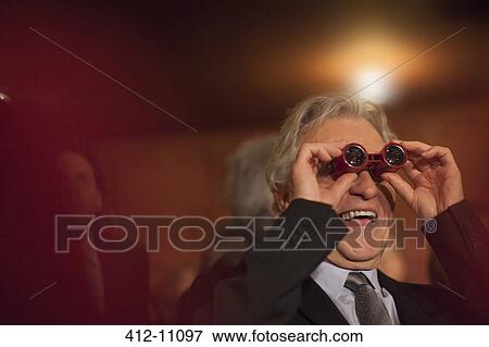 Close up of man using opera glasses in theater View Large Photo Image Stock Photo - Close up of man using opera glasses in theater. Fotosearch